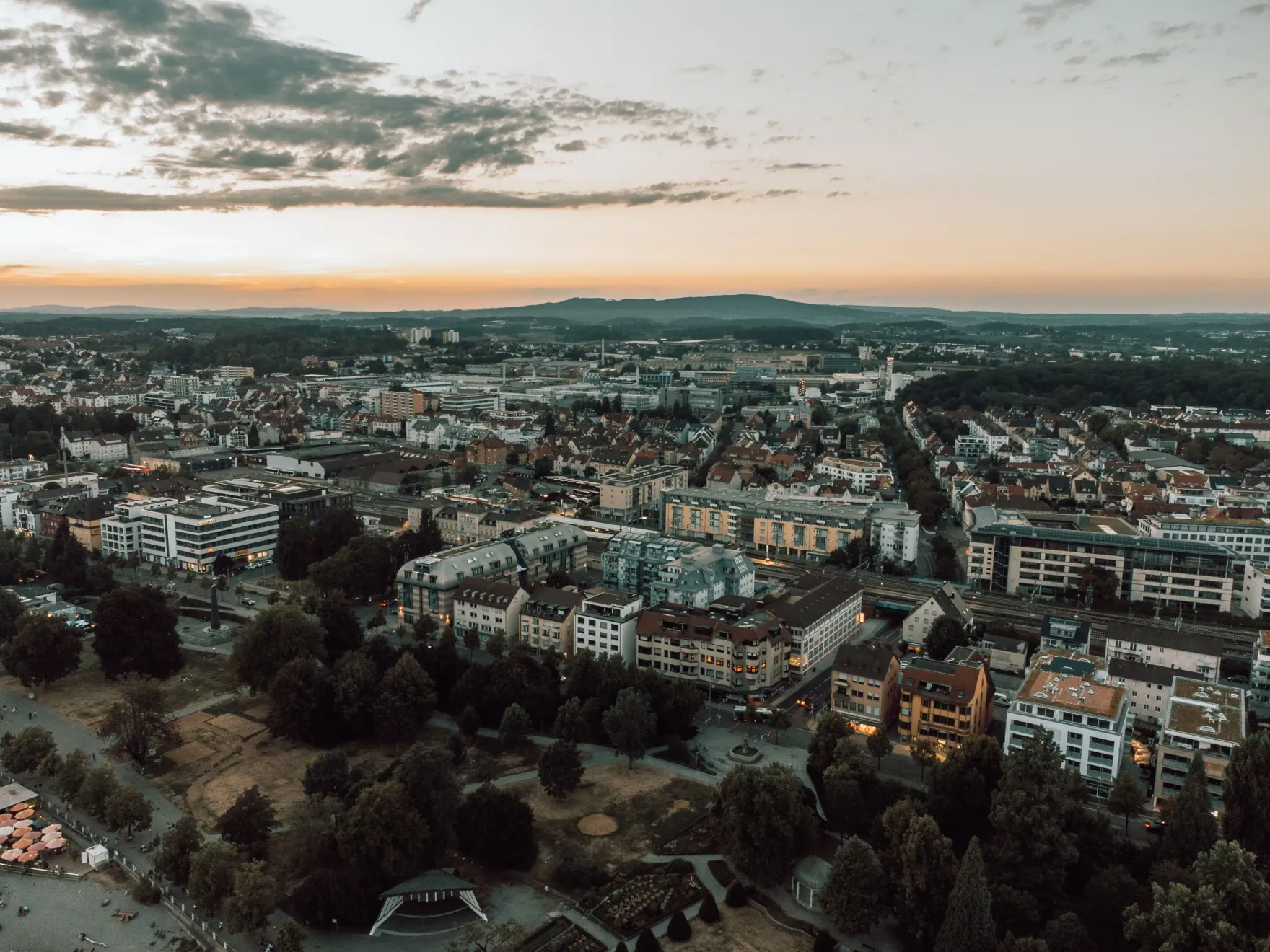 Luftaufnahme der Innenstadt von Bielefeld in der Abenddämmerung mit dem Höhenzug des Teutoburger Walds am Horizont