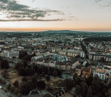 Luftaufnahme der Innenstadt von Bielefeld in der Abenddämmerung mit dem Höhenzug des Teutoburger Walds am Horizont